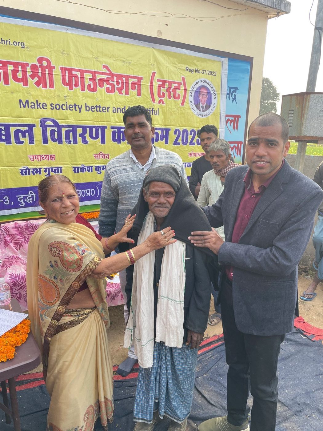Blanket being wrapped around an elderly man in Tedha village